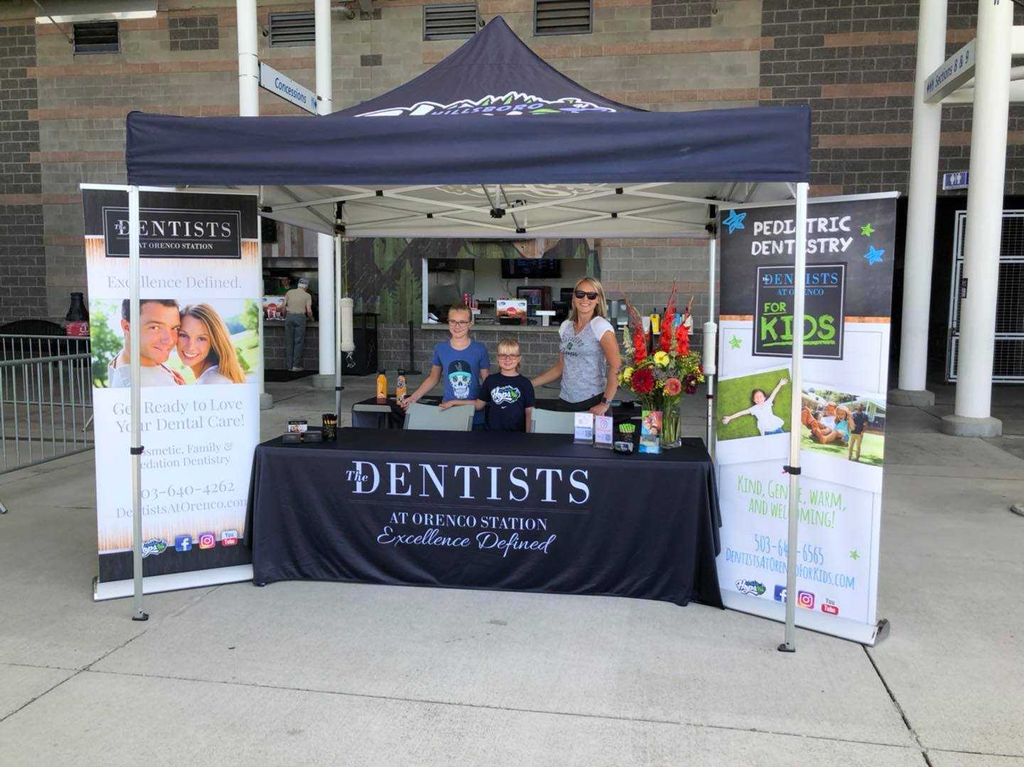 Woman with two children at desk and tent for The Dentists at Orenco Station at Hillsboro community event