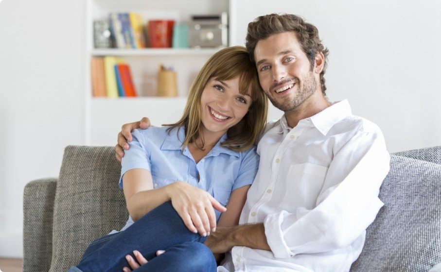 Man and woman on couch smiling with dental crowns in Hillsboro