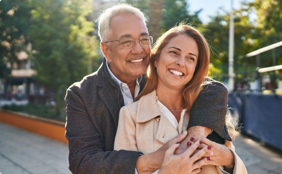 Man and woman hugging and smiling outdoors with dental implants in Hillsboro