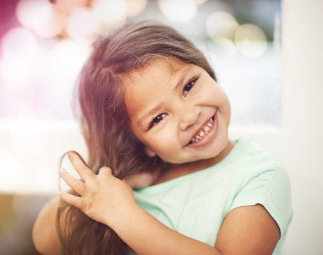 Smiling young girl playing with her hair