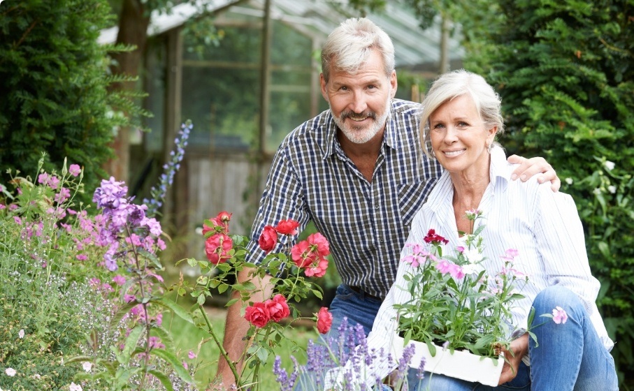 Senior man and woman smiling in their garden after restorative dentistry in Hillsboro
