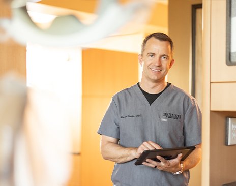 Dentist holding a tablet while smiling at a patient