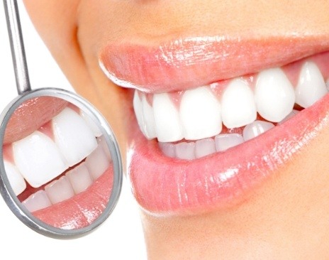 Close up of dental mirror reflecting smile with flawless white teeth