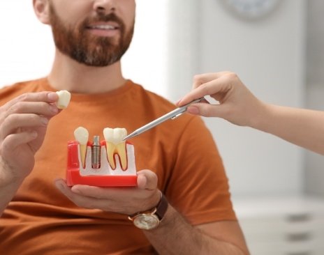 Dentist giving a dental implant model to a patient