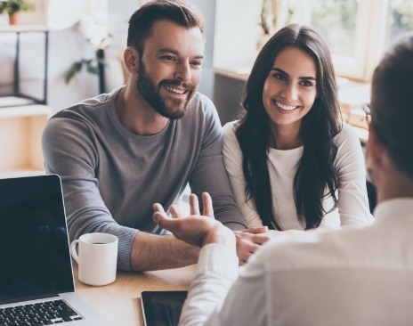 Man and woman talking to person across table