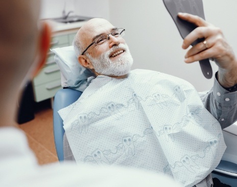 Senior dental patient looking at his smile in mirror