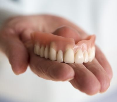 Hand holding a full upper denture