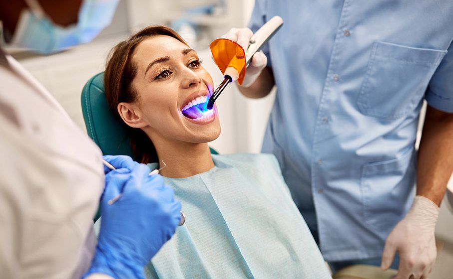 Dentist applying UV light to woman’s tooth