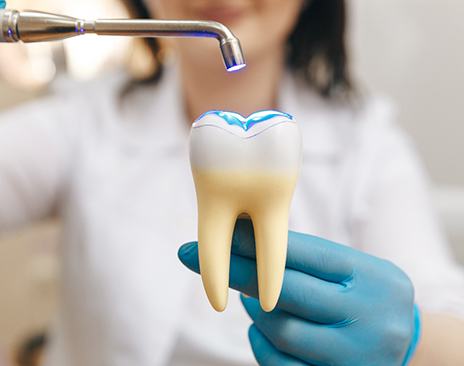 Dentist demonstrating tooth-colored filling on large model tooth