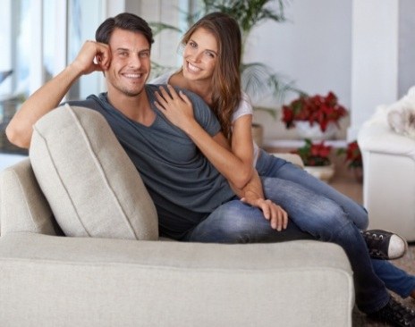 Man and woman snuggling on couch and smiling