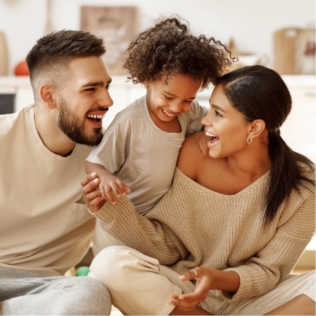 Man and woman laughing on floor with their young child