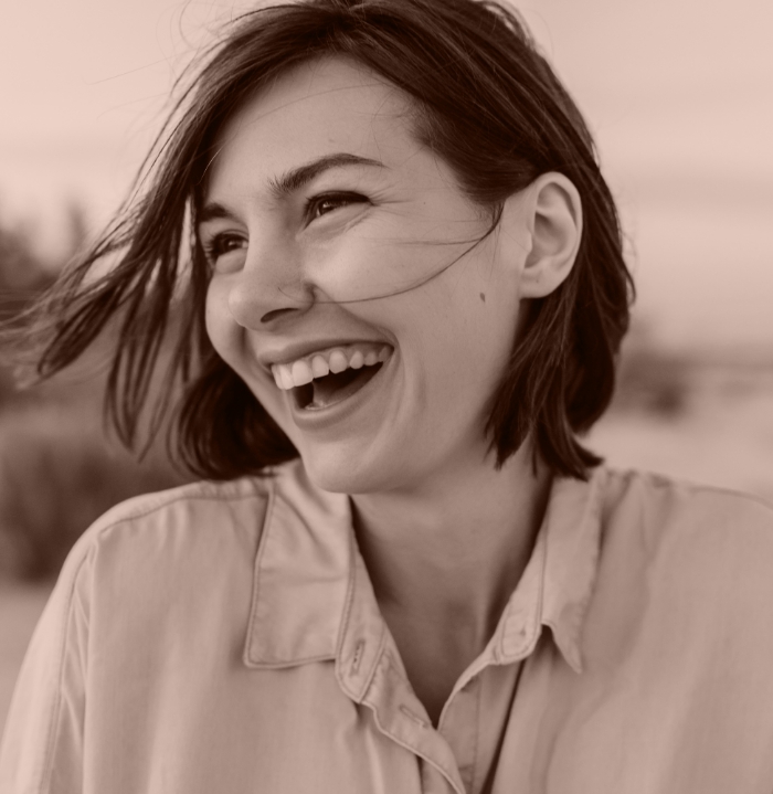 Woman smiling outdoors with her hair blowing in the wind