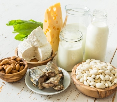 Glasses of milk cheese nuts and other healthy foods on table