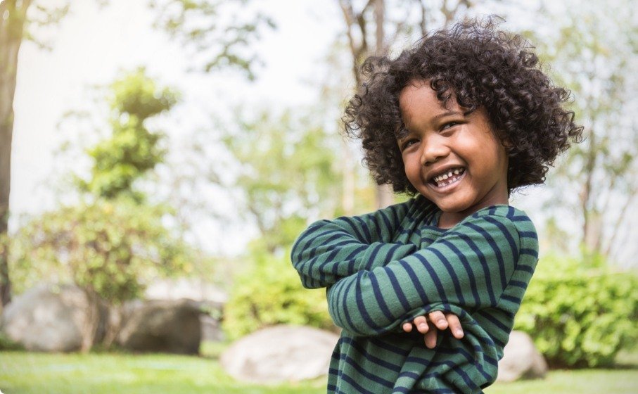 Child grinning outdoors after visiting pediatric dentist in Hillsboro