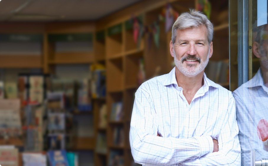 Smiling older man in white collared shirt standing with arms crossed