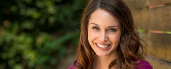 Woman in fuschia blouse smiling after dental services in Hillsboro