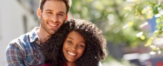 Smiling man and woman hugging outdoors