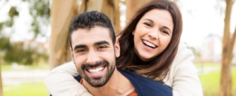 Smiling woman hugging man from behind outdoors