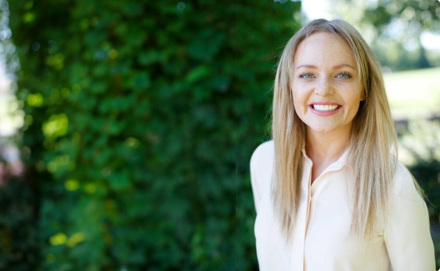 Blonde woman smiling with greenery in background