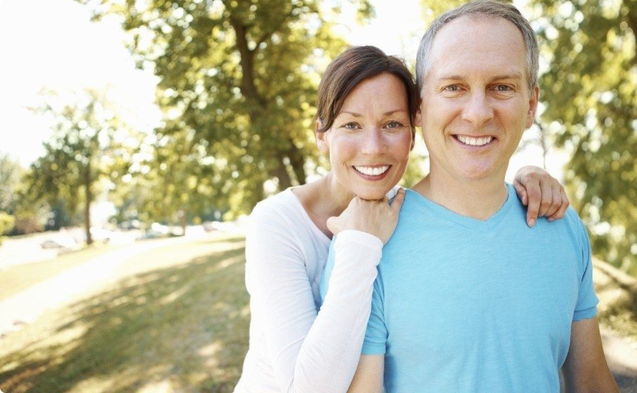 Man and woman smiling in forest after tooth extractions in Hillsboro