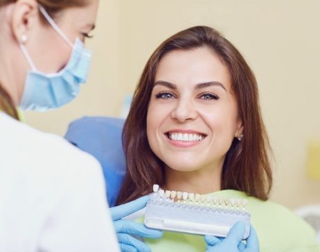 Woman smiling in dental chair while getting veneers