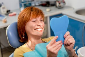 Woman in dental chair looking at smile