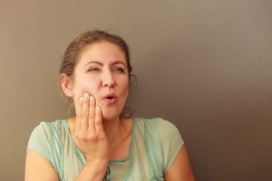 woman holding face painfully from toothache