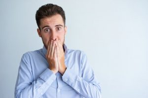 Concerned man covering his crooked teeth with his hands