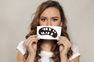 Woman holding card of crooked frown in front of her face