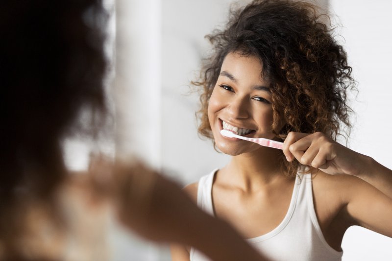 A pretty lady brushing her teeth in front of a mirror
