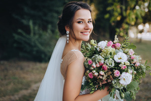 Woman in bridal gown smiling and holding a bouquet